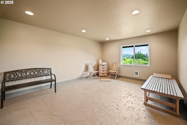 living area featuring a textured ceiling, marble finish floor, recessed lighting, baseboards, and visible vents