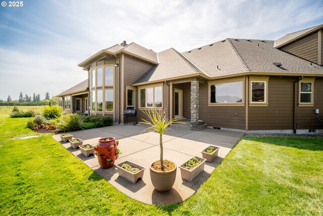 rear view of property with a lawn, a patio area, and roof with shingles