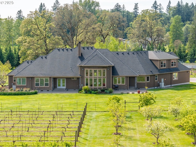 rear view of house featuring fence, a chimney, french doors, a patio, and a lawn