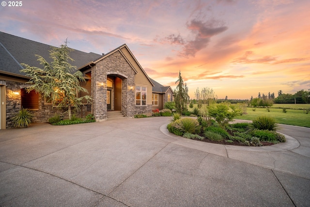 french country inspired facade with curved driveway and stone siding