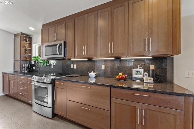 kitchen with dark stone countertops, appliances with stainless steel finishes, tasteful backsplash, and light tile patterned floors