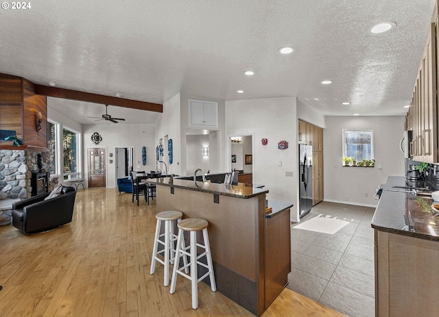 kitchen with light hardwood / wood-style floors, stainless steel appliances, dark stone counters, and a textured ceiling