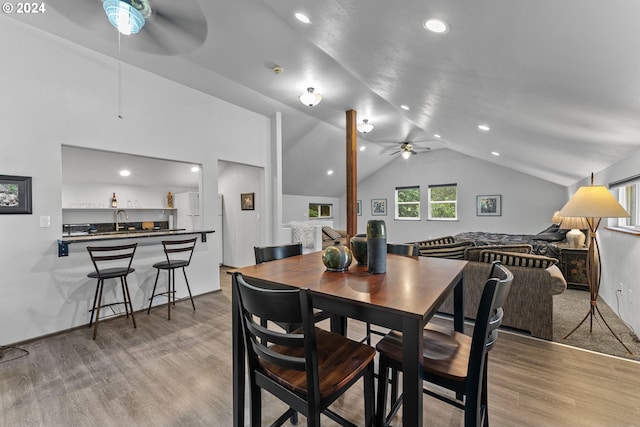 dining room with ceiling fan, vaulted ceiling, indoor wet bar, and light wood-type flooring