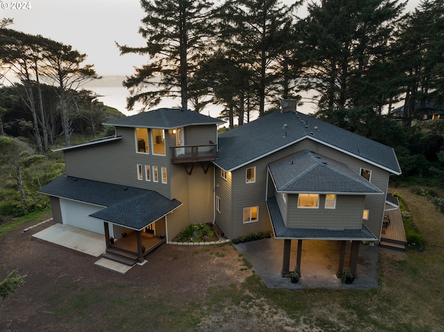 back house at dusk featuring a balcony and a deck