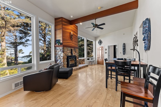 living room with ceiling fan, plenty of natural light, light hardwood / wood-style flooring, and a wood stove