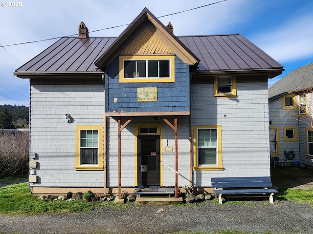 view of front facade with a standing seam roof, metal roof, and a chimney