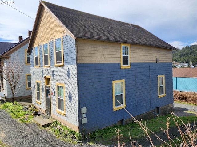 view of side of home featuring roof with shingles and a chimney