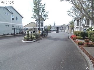 view of road with a residential view, a gate, curbs, and a gated entry