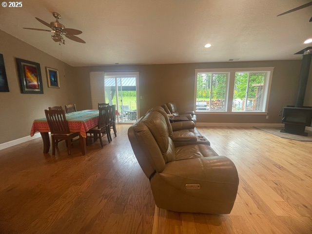 24945 Oak Ln, Elmira, OR 97437 - living area featuring ceiling fan, a wood stove, light wood-style floors, baseboards, and recessed lighting