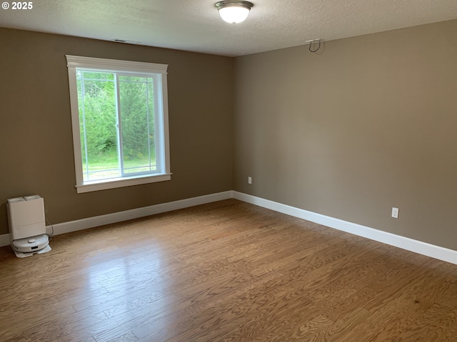 24945 Oak Ln, Elmira, OR 97437 - empty room with healthy amount of natural light, wood finished floors, baseboards, and a textured ceiling