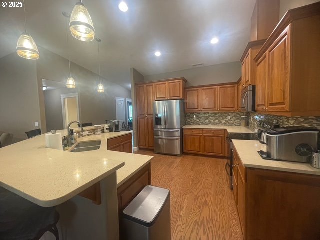 24945 Oak Ln, Elmira, OR 97437 - kitchen with stainless steel appliances, a sink, brown cabinets, light wood-type flooring, and decorative backsplash