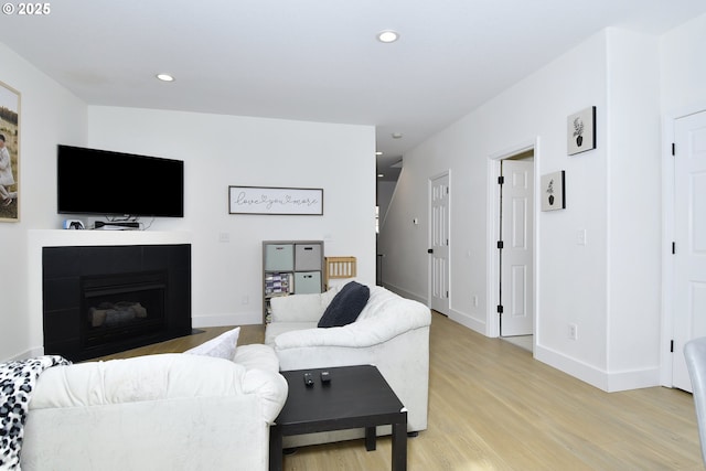 living area featuring baseboards, light wood finished floors, a fireplace with flush hearth, and recessed lighting