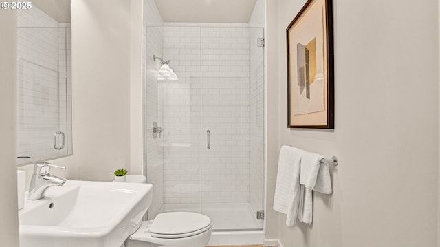 bathroom with a shower with shower door, sink, and toilet