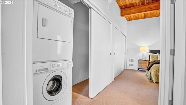 clothes washing area featuring wood ceiling, stacked washer and clothes dryer, and light carpet