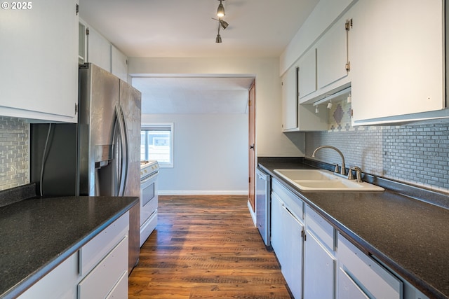 kitchen featuring dark wood finished floors, a sink, dishwasher, dark countertops, and tasteful backsplash