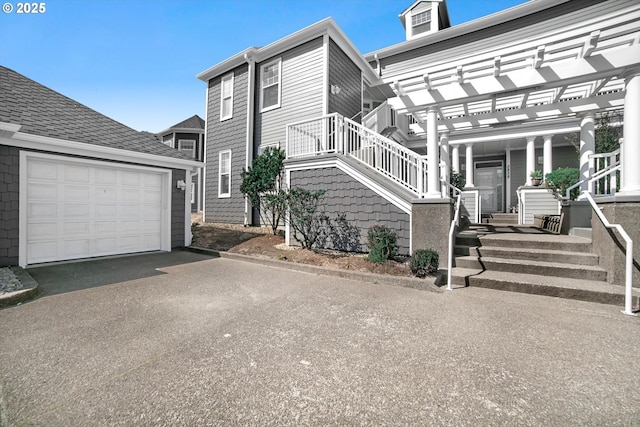 view of property exterior with a pergola, driveway, and a garage