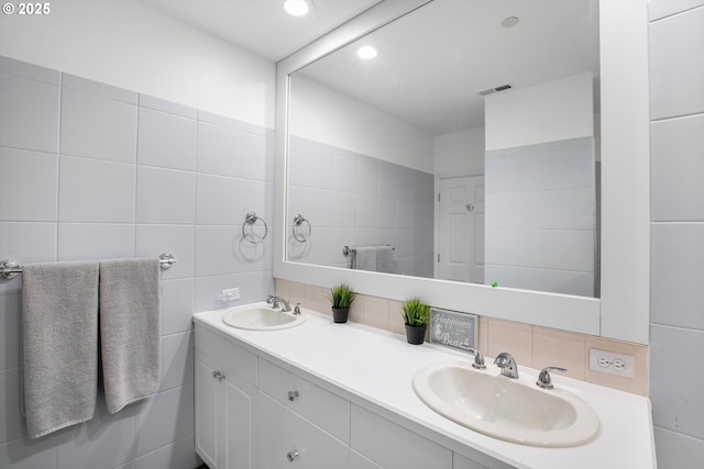 bathroom with tile walls, a sink, decorative backsplash, and visible vents