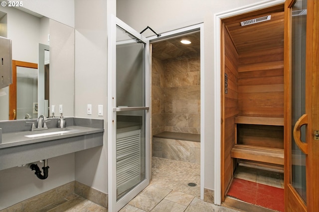 bathroom with a tile shower and a sink