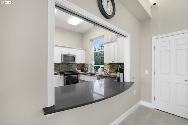 kitchen featuring appliances with stainless steel finishes, dark countertops, white cabinets, and backsplash