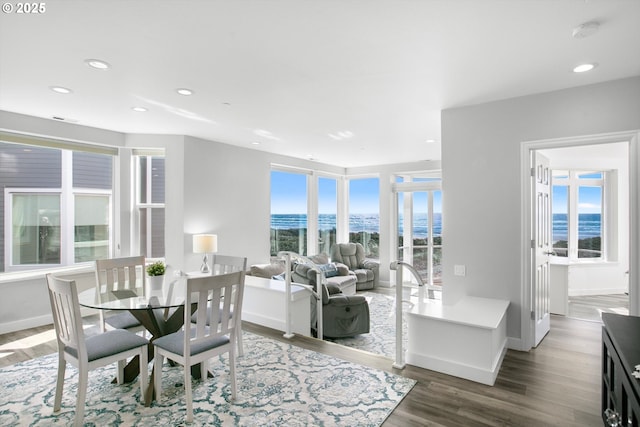 dining area featuring recessed lighting, a water view, wood finished floors, and baseboards