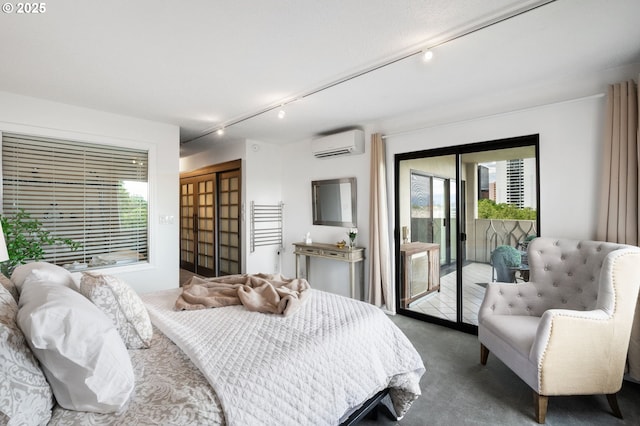 bedroom featuring rail lighting, access to outside, an AC wall unit, and dark colored carpet