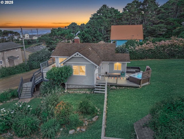 5353 SW Neal Ave, Waldport, OR 97394 - back of property at dusk with a yard, a wooden deck, stairs, and a chimney