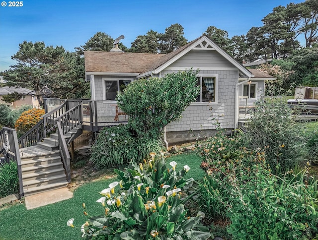 5353 SW Neal Ave, Waldport, OR 97394 - view of front of house with a wooden deck, stairs, a shingled roof, a front lawn, and a chimney