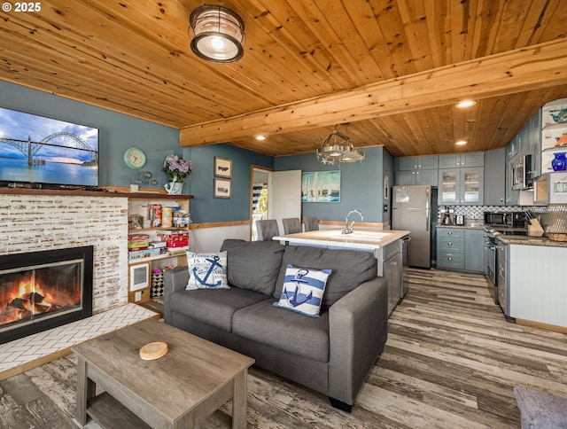 5353 SW Neal Ave, Waldport, OR 97394 - living area featuring light wood-style flooring, a glass covered fireplace, a chandelier, and a wood ceiling with exposed beams