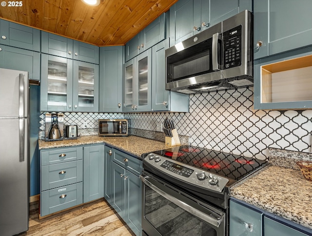 5353 SW Neal Ave, Waldport, OR 97394 - kitchen featuring appliances with stainless steel finishes, tasteful backsplash, wood ceiling, light wood-style flooring, and light stone countertops