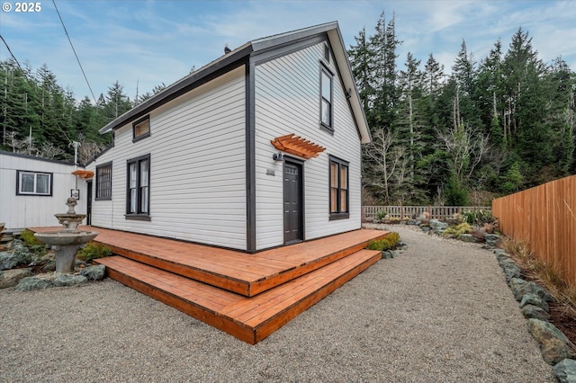 view of property exterior featuring fence and a wooden deck