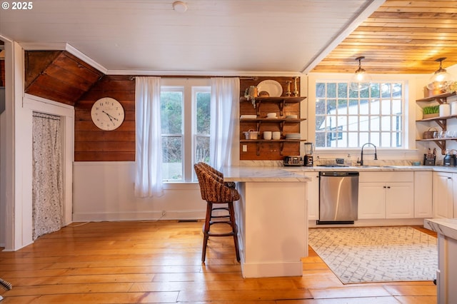 kitchen with a kitchen breakfast bar, light countertops, hanging light fixtures, dishwasher, and open shelves