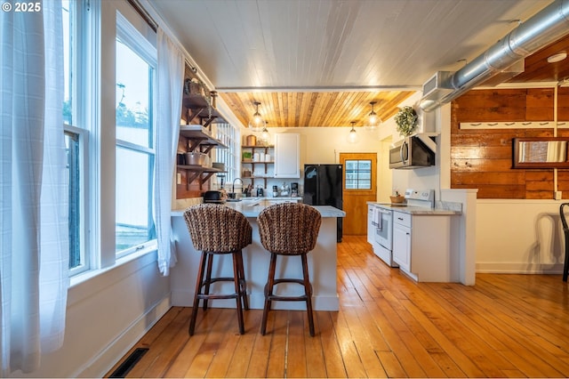 kitchen featuring stainless steel microwave, light countertops, white electric range, white cabinetry, and open shelves