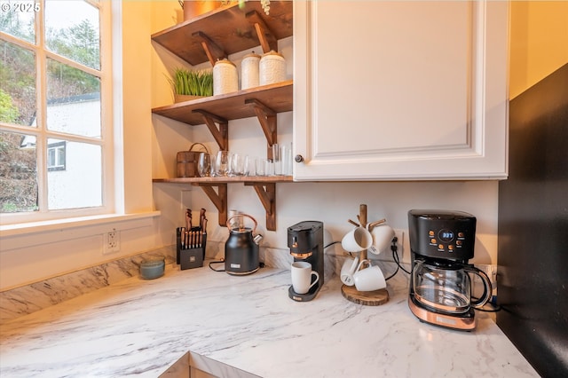 details with white cabinetry, open shelves, and light stone counters