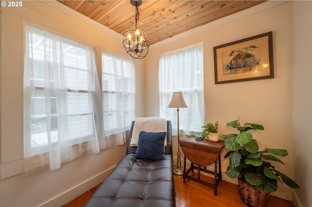 sitting room featuring crown molding, wood finished floors, a chandelier, wooden ceiling, and baseboards