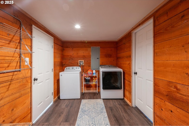 laundry area featuring laundry area, electric panel, wooden walls, dark wood finished floors, and washing machine and dryer