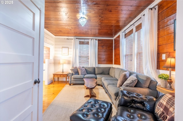 living room featuring light wood finished floors, wood walls, and wooden ceiling