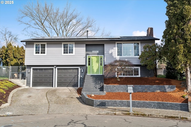 bi-level home featuring a garage and solar panels