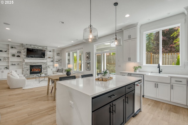 11723 NW Sadie St, Portland, OR 97229 - kitchen featuring light wood-type flooring, a stone fireplace, light countertops, hanging light fixtures, and recessed lighting