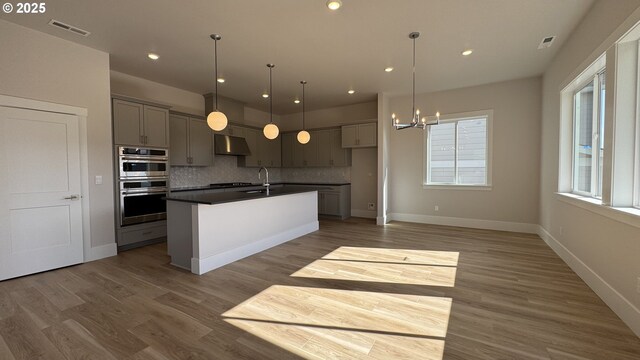 11699 SW 178th Dr, Beaverton, OR 97007 - kitchen with under cabinet range hood, gray cabinetry, dark countertops, backsplash, and light wood-style floors