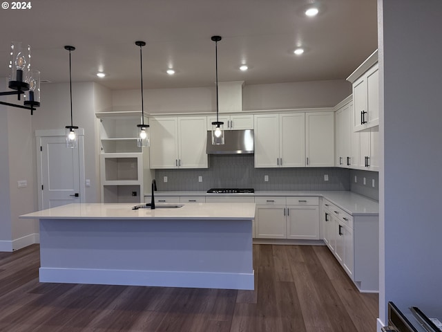 kitchen with hanging light fixtures, white cabinetry, sink, and a kitchen island with sink