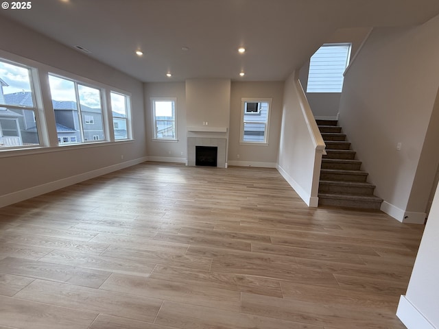 unfurnished living room with light wood-type flooring, stairs, baseboards, and recessed lighting