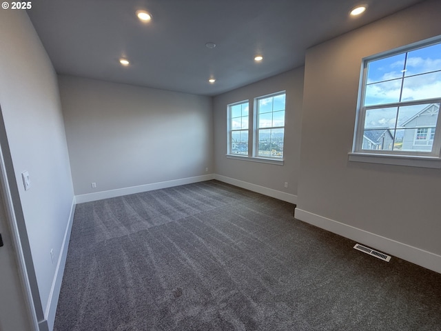 empty room with baseboards, visible vents, dark colored carpet, and recessed lighting