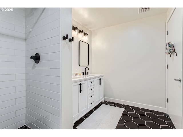 full bathroom featuring visible vents, vanity, baseboards, tile patterned floors, and tiled shower