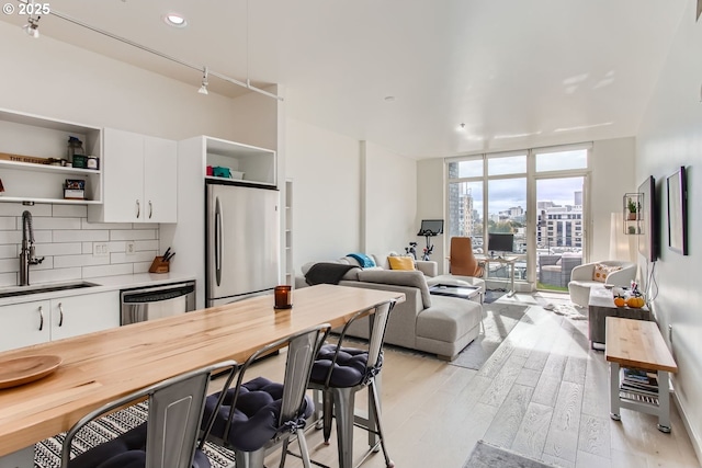 1255 NW 9th Ave Unit 806, Portland, OR 97209 - kitchen with appliances with stainless steel finishes, open shelves, light wood-type flooring, a sink, and a breakfast bar