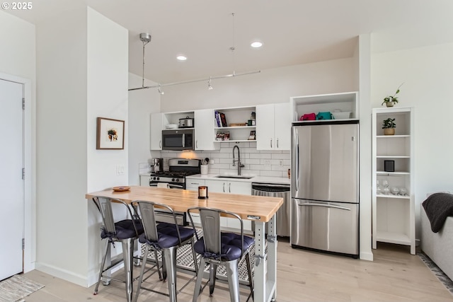 kitchen featuring open shelves, white cabinetry, a sink, backsplash, and stainless steel appliances