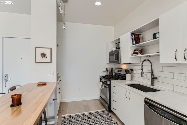 1255 NW 9th Ave Unit 806, Portland, OR 97209 - kitchen with open shelves, appliances with stainless steel finishes, a sink, white cabinetry, and backsplash