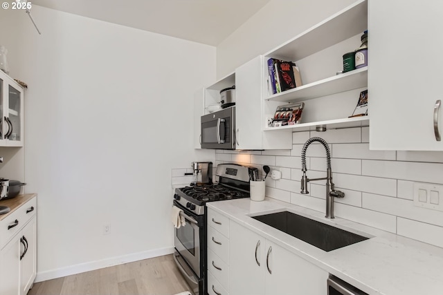1255 NW 9th Ave Unit 806, Portland, OR 97209 - kitchen featuring tasteful backsplash, light stone countertops, light wood-type flooring, a sink, and stainless steel gas range