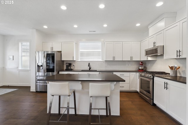 14878 NW Olive St, Portland, OR 97229 - kitchen featuring decorative backsplash, a kitchen breakfast bar, dark countertops, a center island, and stainless steel appliances