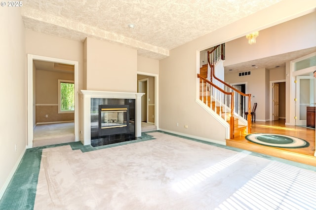 2525 NW 141st Pl, Portland, OR 97229 - unfurnished living room with stairway, carpet floors, baseboards, a tiled fireplace, and a textured ceiling