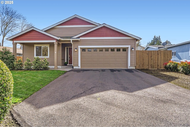 view of front facade with aphalt driveway, fence, a garage, and a front lawn